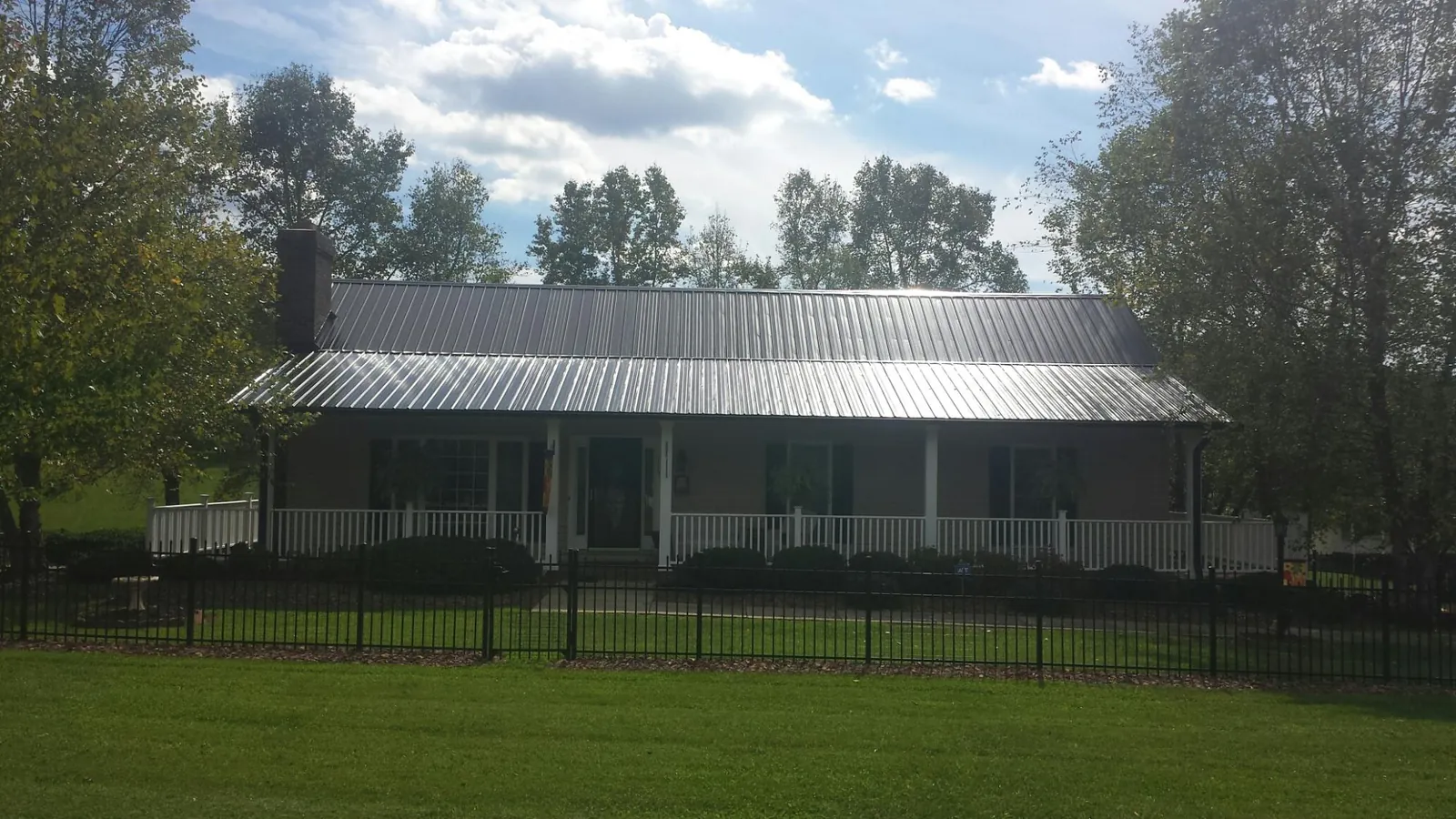 Gray metal roof on a brick ranch with a full width front porch — Gutter Guard Installation work by our crew in Hillside