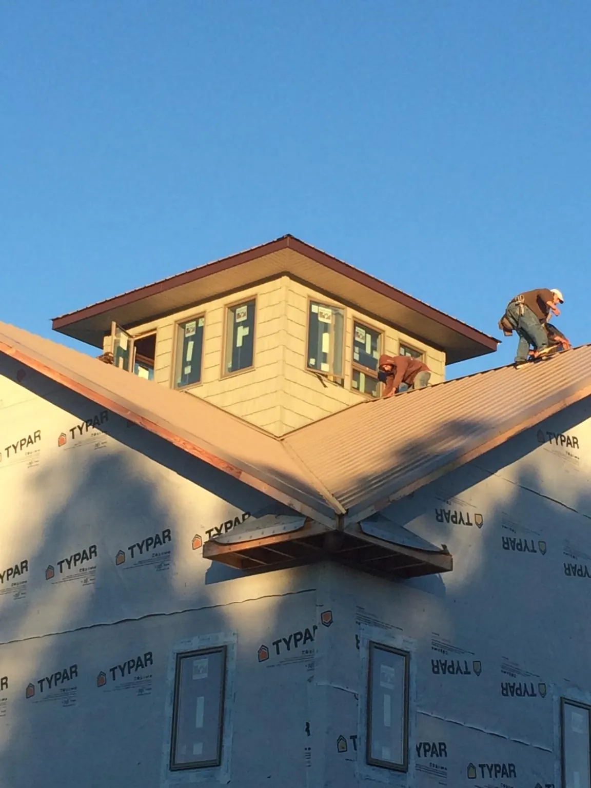 Roofers working around a rooftop cupola on a new metal roof at sunset — Roof Waterproofing in Hillside by Roofing Brothers
